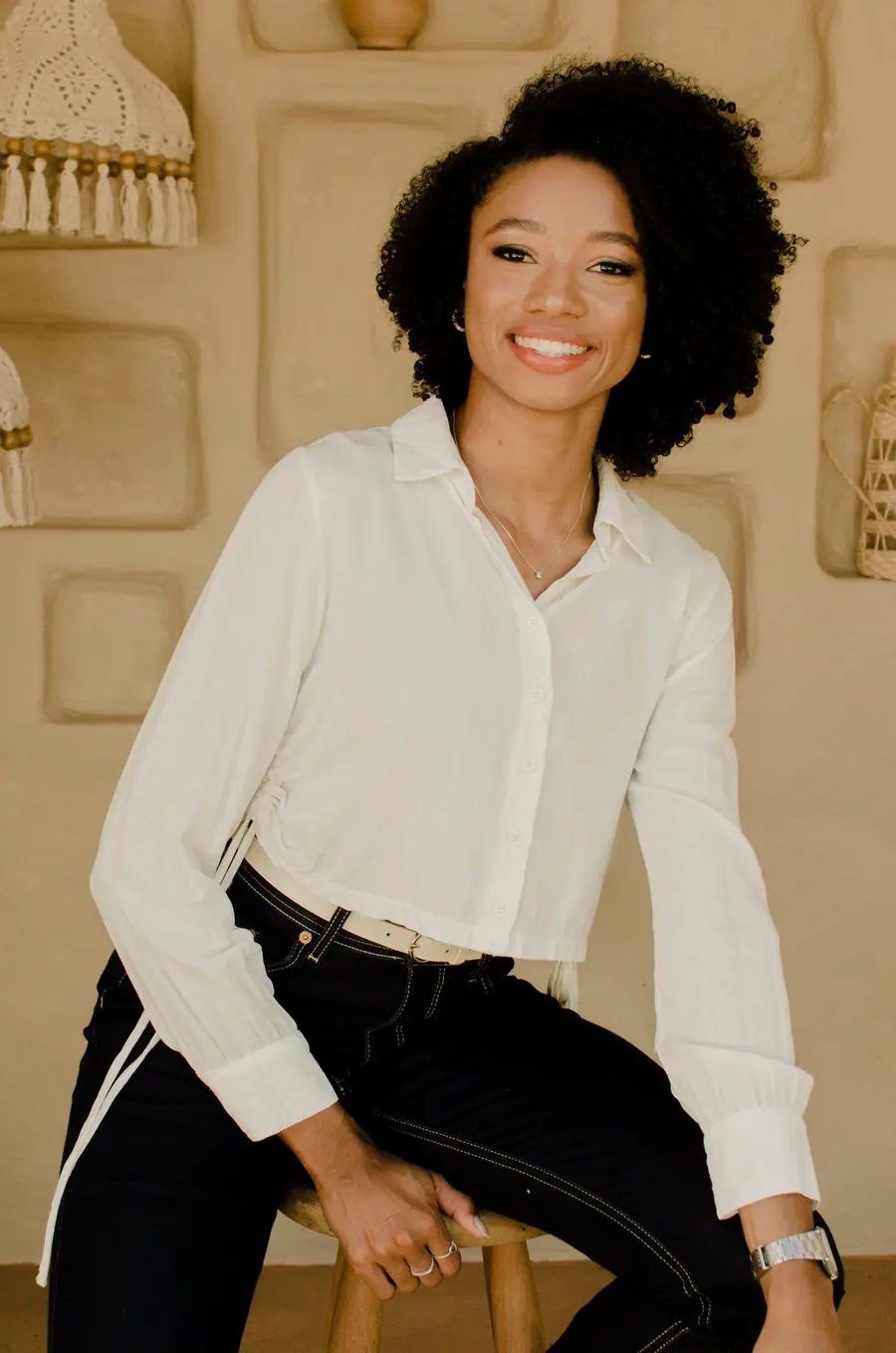 Gabby Faustino sentada em um banco, sorrindo para a câmera